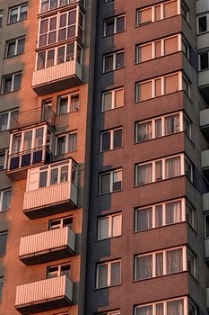 A high-rise residential building with numerous balconies lit by the warm glow of a sunset.