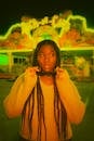 Woman with Afro-American Hairstyle Standing Before Restaurant with Big Illumination in Front