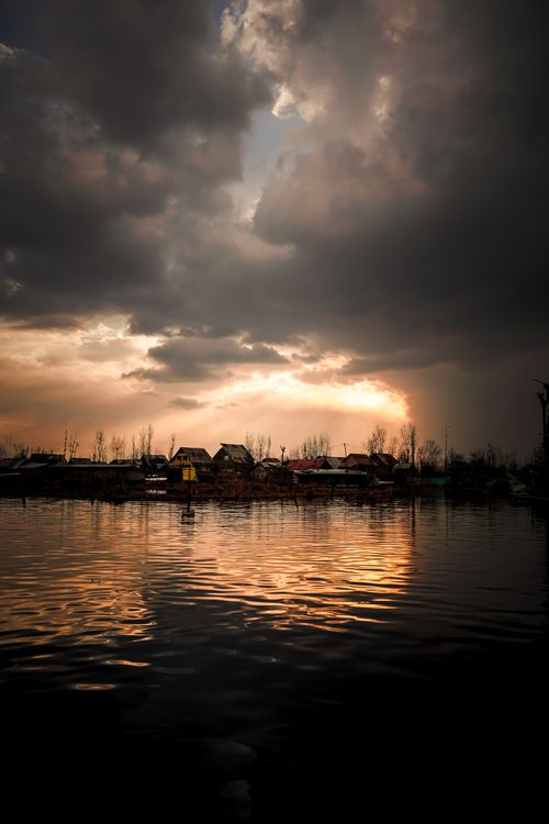Free A stunning sunset with dramatic clouds reflecting on a calm lake surface, creating a peaceful atmosphere. Stock Photo