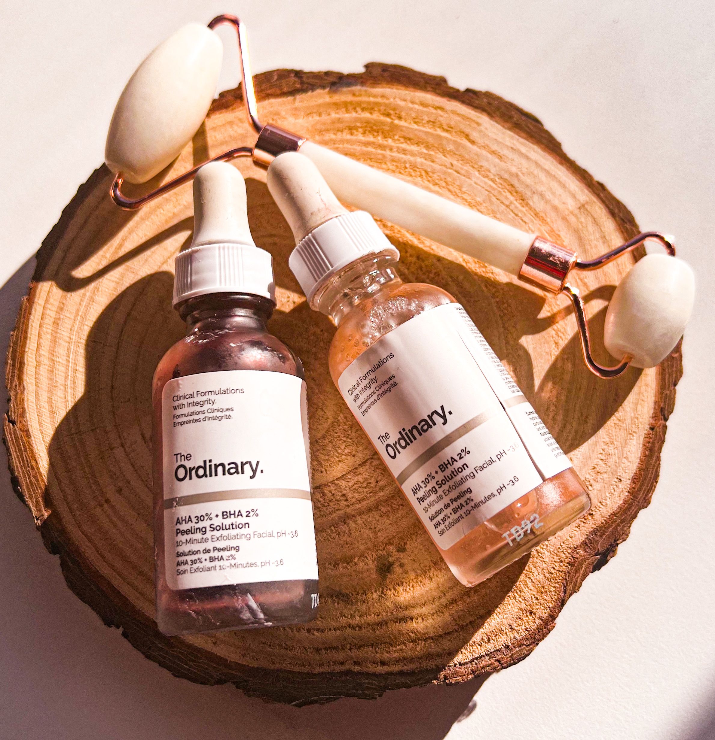 Composição plana de produtos de skincare e rolo facial em fatia de madeira natural para beleza e autocuidado.