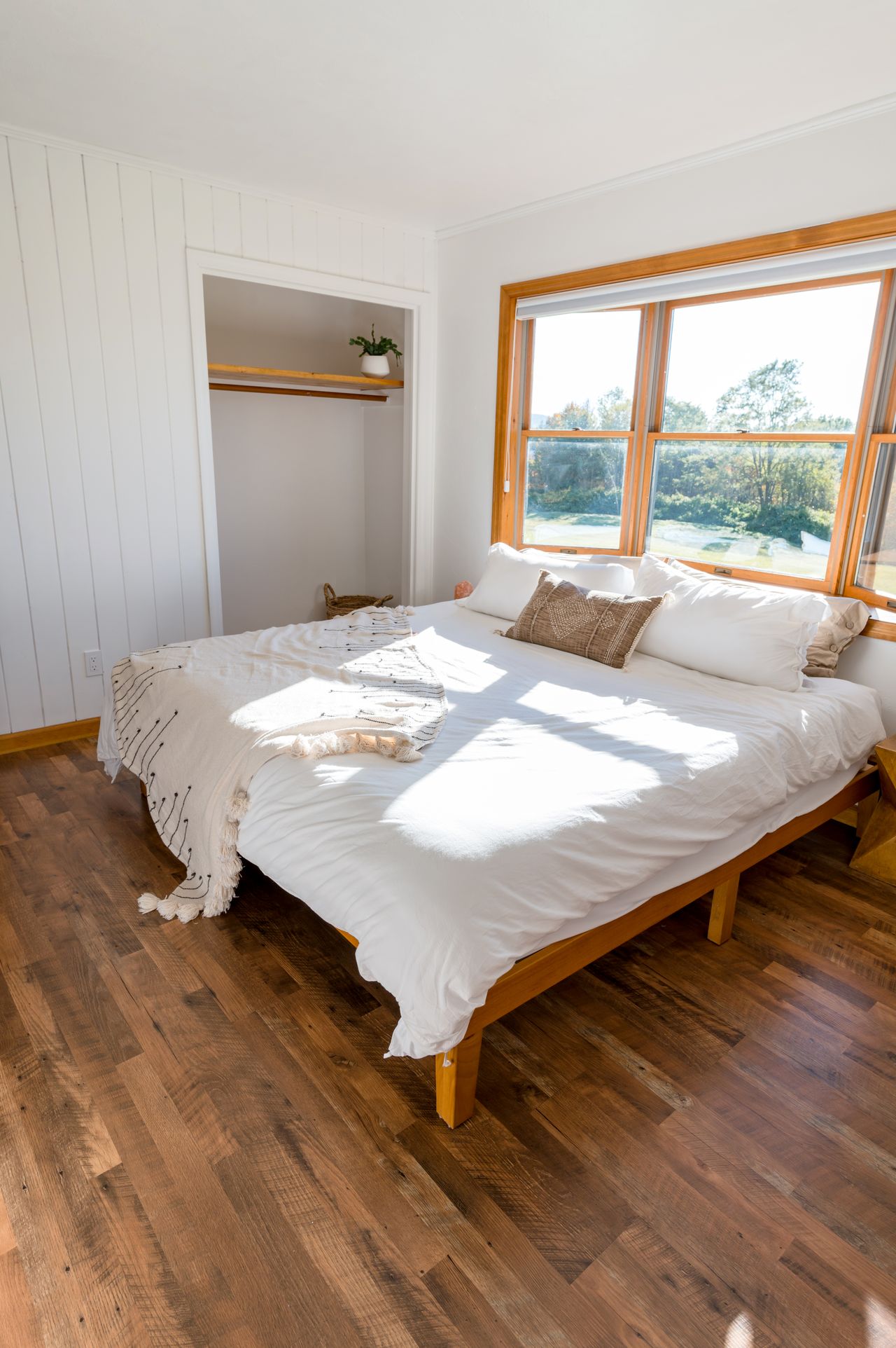 Bright bedroom with white bedding and a natural wood bed frame