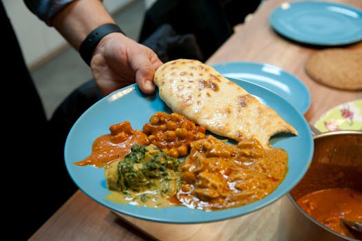 A vibrant blue plate featuring a variety of Indian curries and naan bread, served indoors.