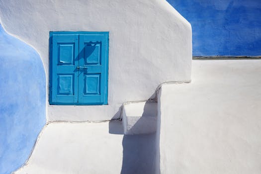 Bright white and blue geometric architecture in Santorini, featuring a traditional blue wooden door.