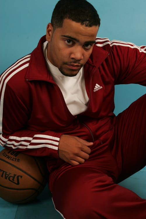 Man in a Tracksuit Sitting by a Basketball