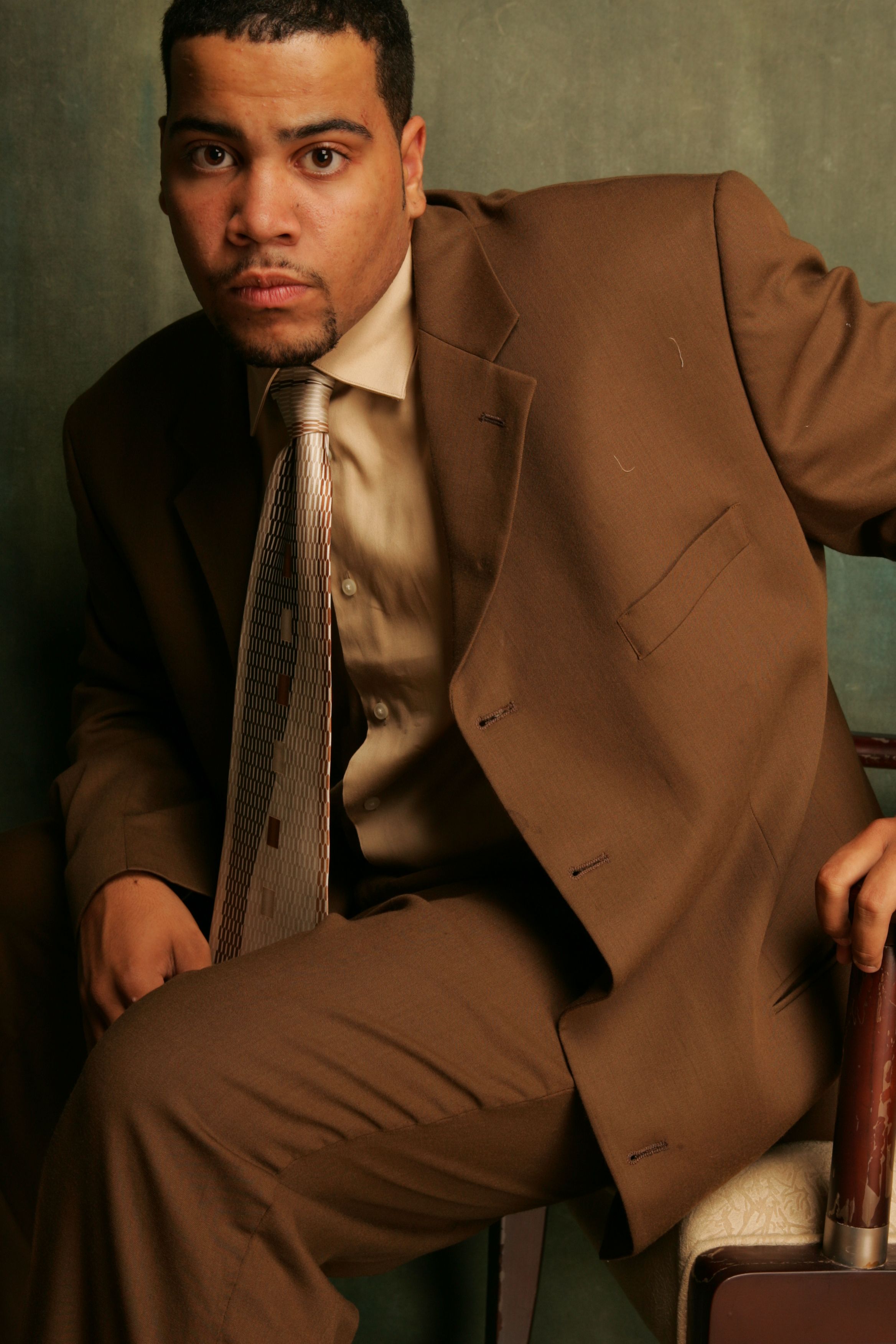 Business professional sitting in a brown suit, conveying confidence and style.