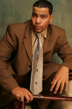 Professional portrait of a man in a brown suit posing confidently with a neutral expression.