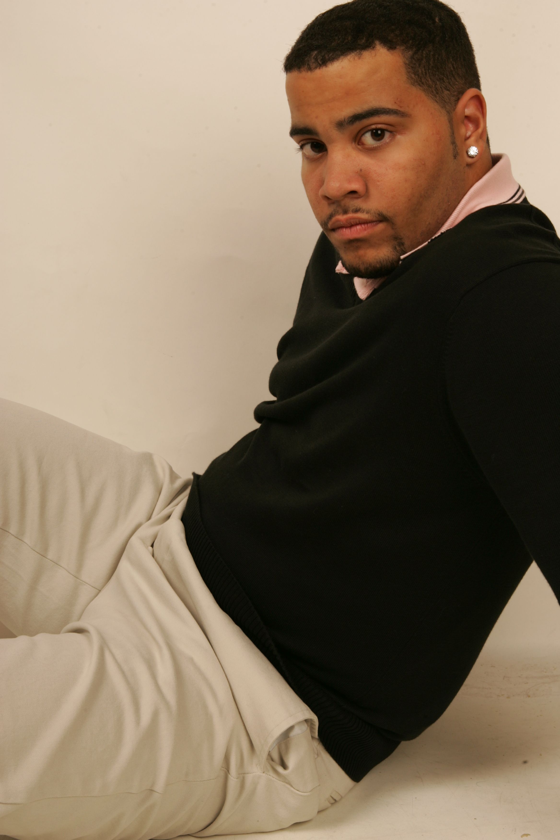 A confident young man sitting in a relaxed pose during a studio photoshoot.