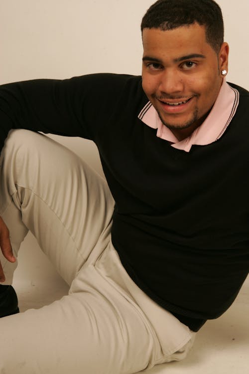 Man in Black Sweater Sitting on the Floor while Smiling at the Camera