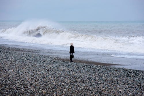 Person in Black Jacket Standing on Seashore