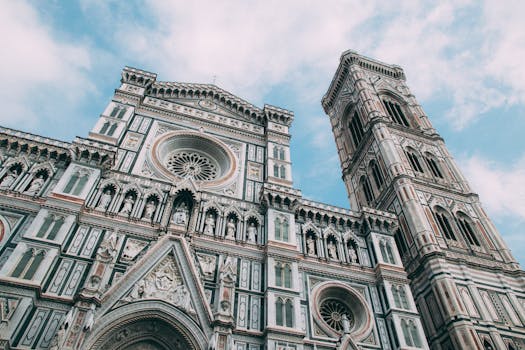 Capture of the Florence Cathedral's ornate facade and bell tower against a blue sky in Italy.