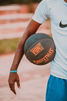 A person holding a basketball outside on a sunny day, featuring a casual sporty vibe.