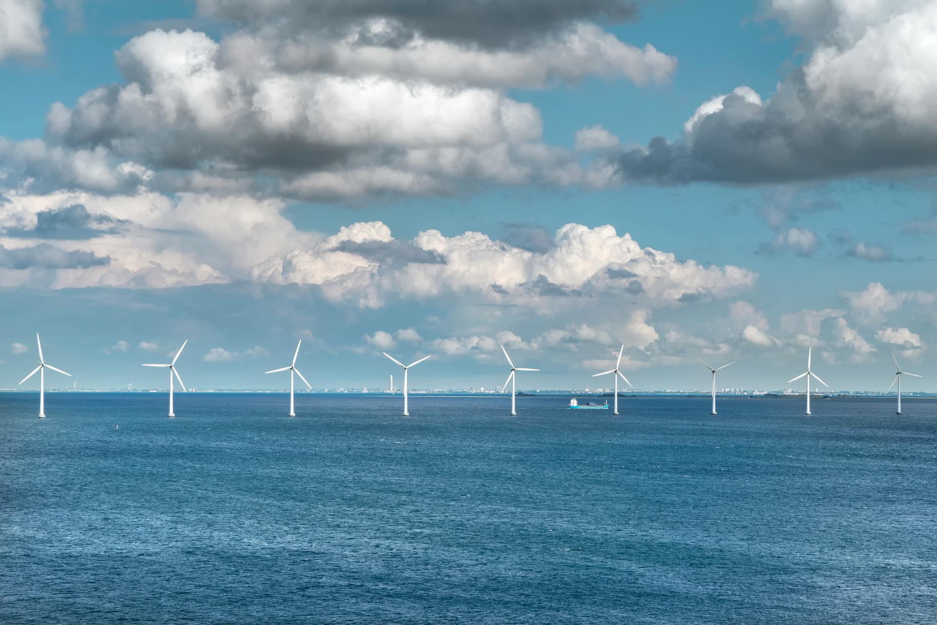 A serene view of offshore wind turbines generating renewable energy under a blue sky with scattered clouds.