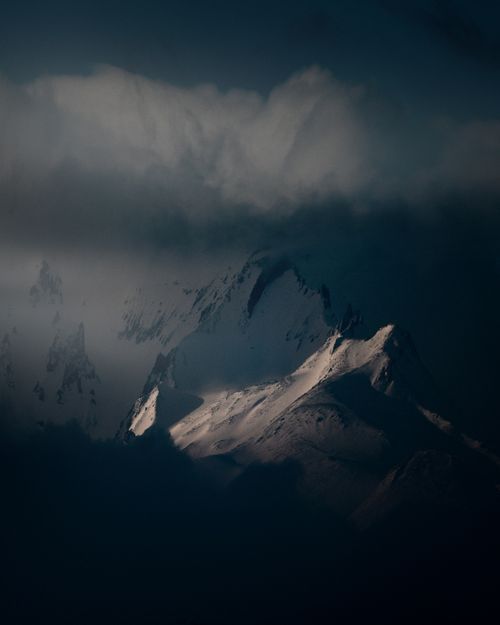 Free Dramatic view of snow-covered peaks surrounded by fog and clouds, perfect for a moody landscape. Stock Photo
