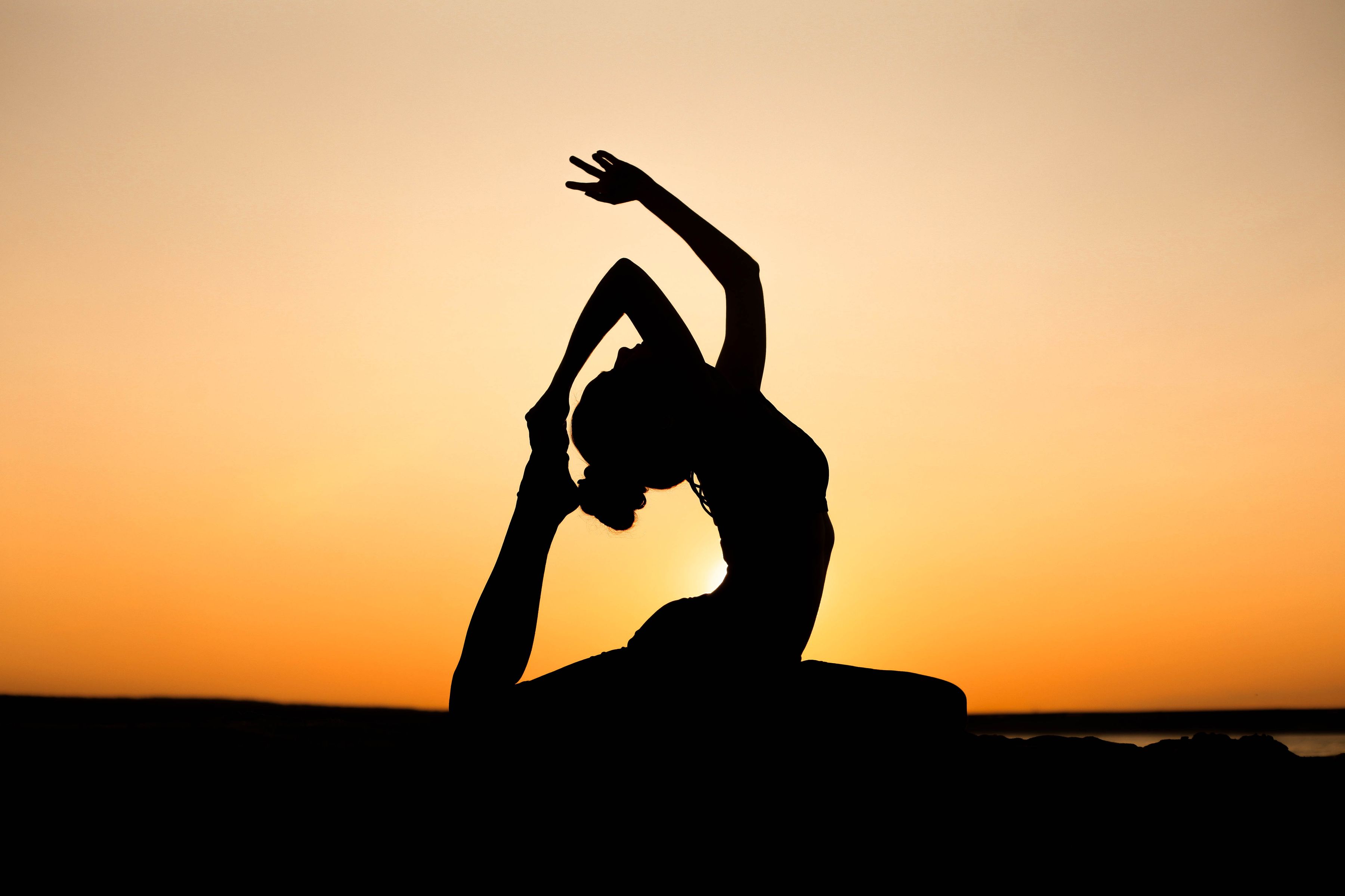 Silhouette en posture de yoga face au soleil couchant