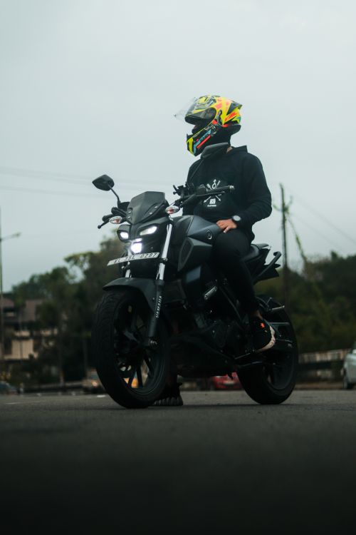 Free A motorcyclist wearing a colorful helmet rides on a road in India. Stock Photo
