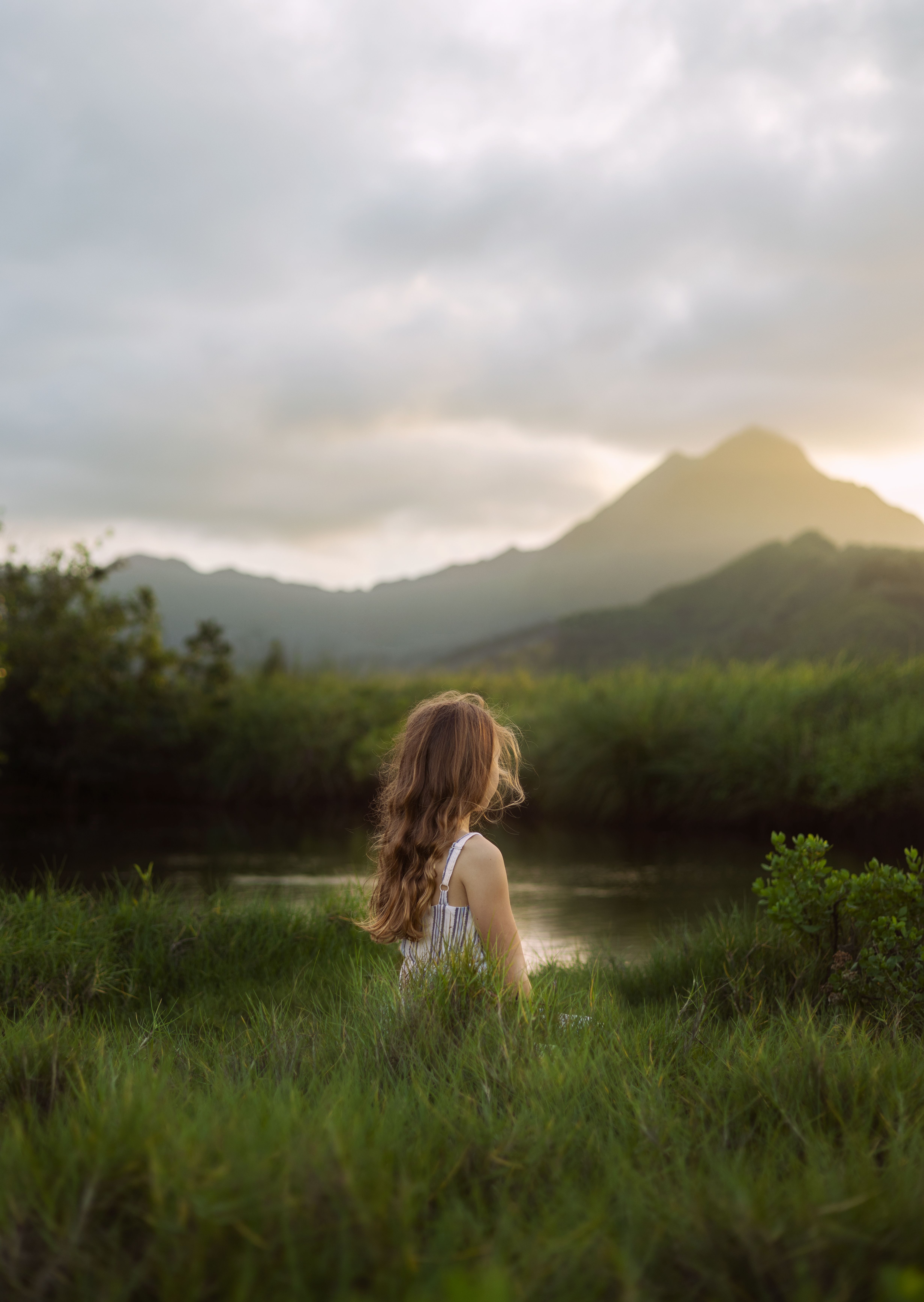 A Girl Standing on a Grass Field Near a Lake · Free Stock Photo