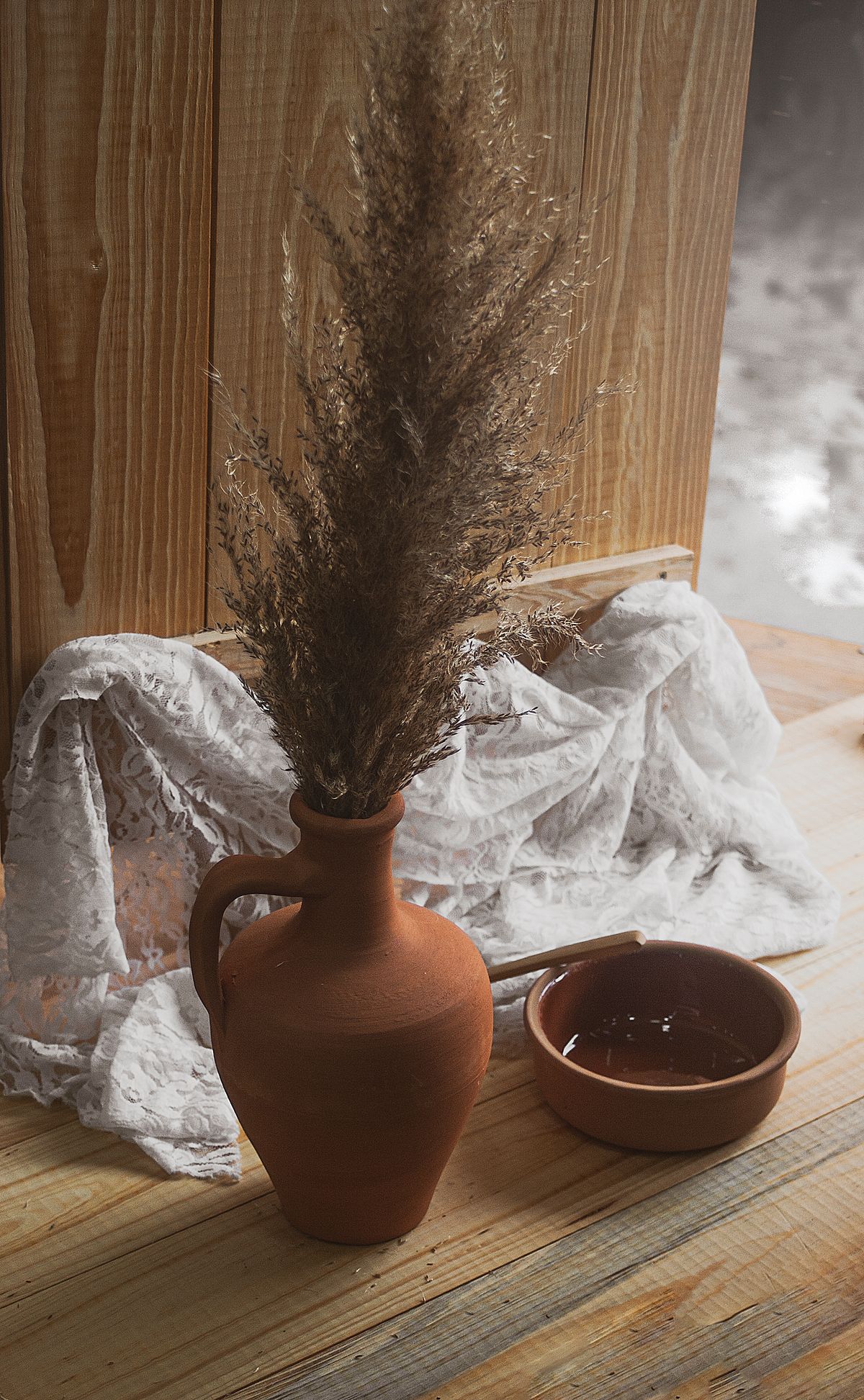 Terracotta vase with pampas grass beside a clay bowl