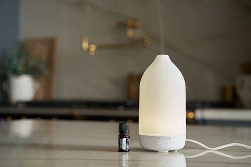 A Bottle of Essential Oil and Essential Oil Diffuser Standing in a Kitchen 