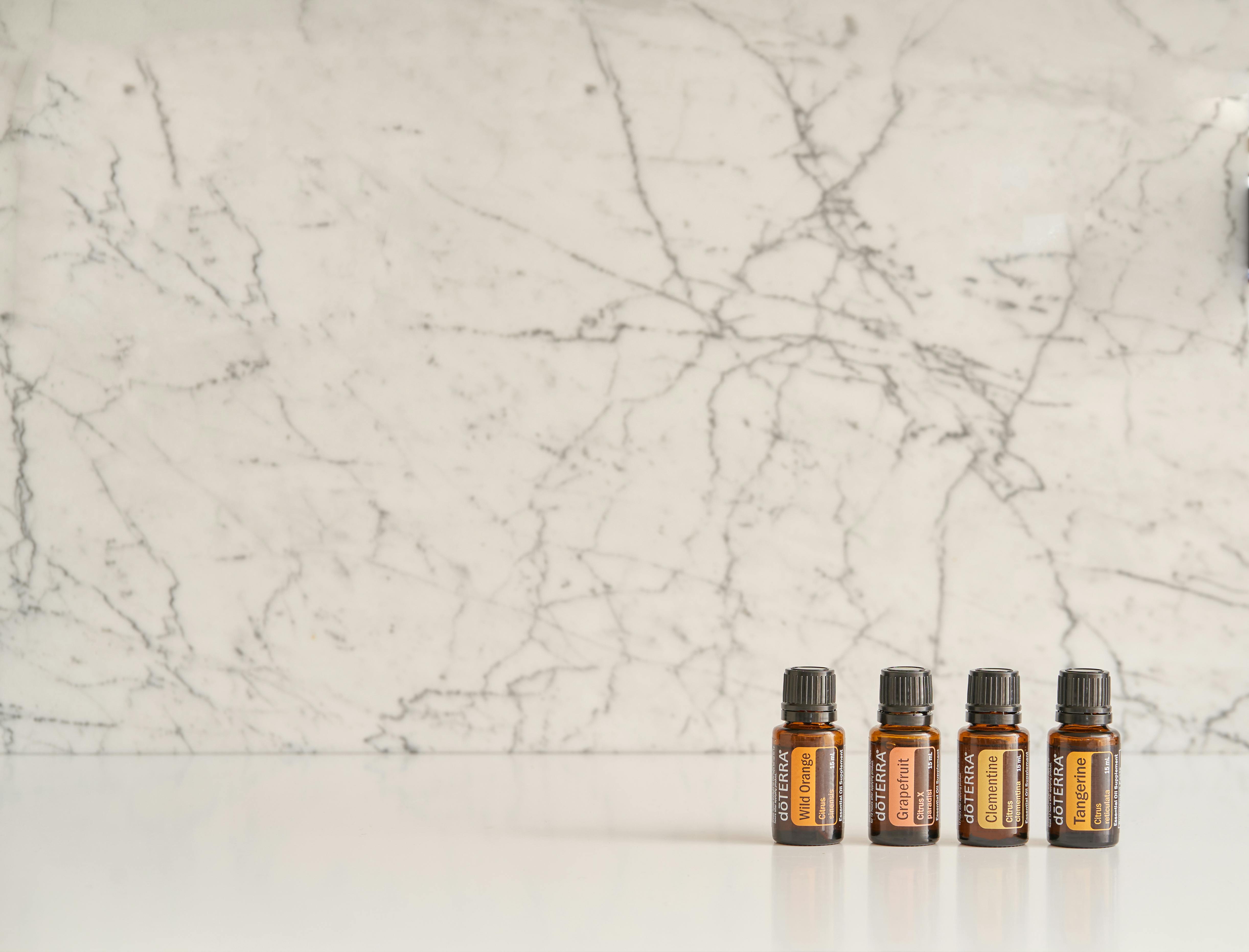 Four essential oil bottles on a white marble surface, perfect for wellness themes.