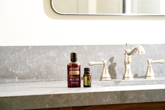 Beautiful display of essential oils on a modern bathroom countertop with a stylish faucet.