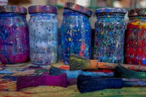 Free Vibrant paint-splattered jars and brushes in an artistic setup Stock Photo