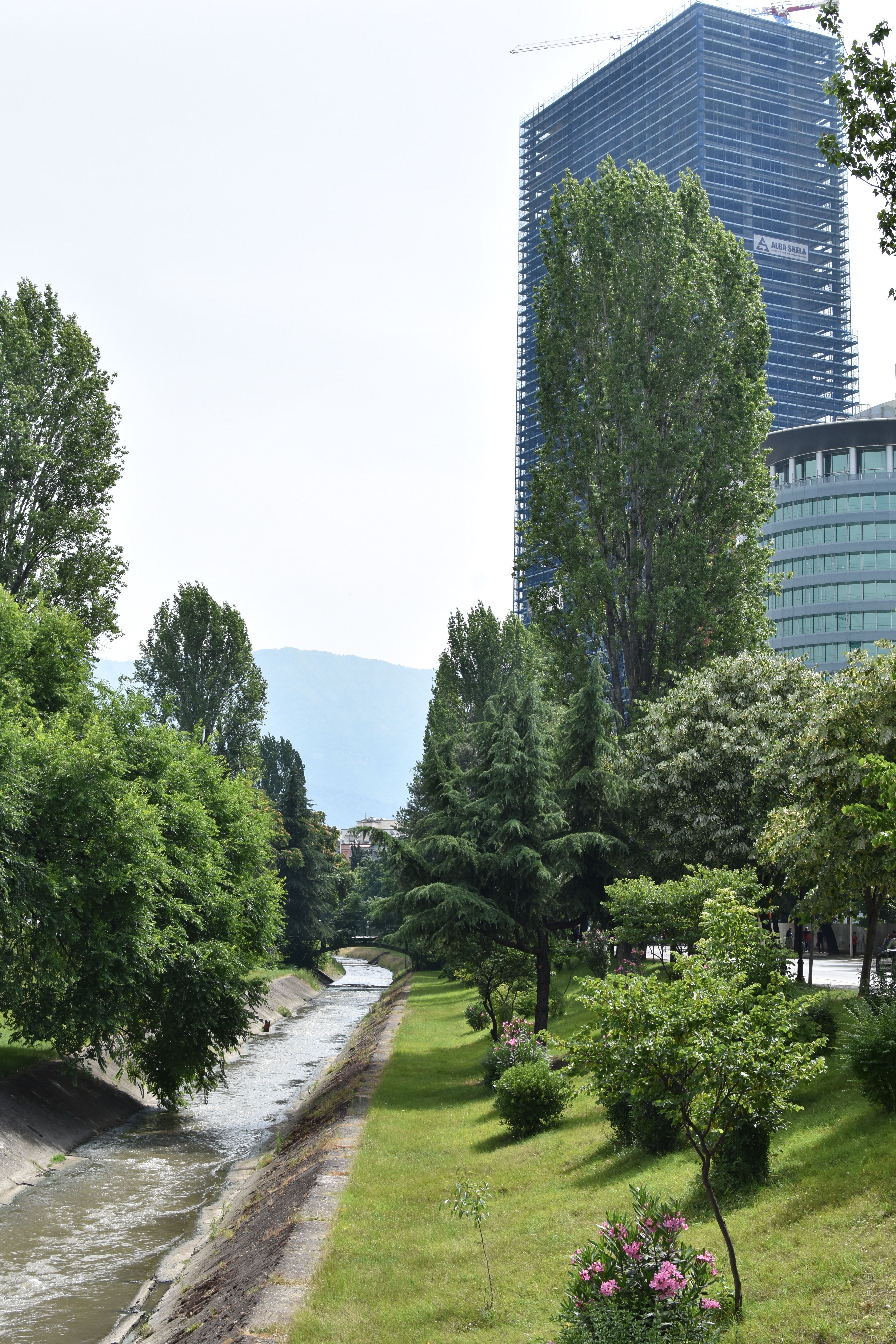 A scenic view of a skyscraper and lush park in Tirana, Albania.