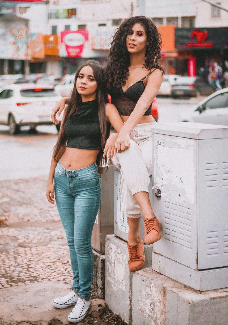 Two Women Sitting And Standing Near Metal Cabinets
