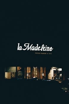 Illuminated facade of La Madeleine French Bakery & Café at night, creating a cozy ambiance.