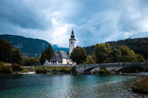 Free Picturesque view of St. John the Baptist Church and bridge over Lake Bohinj in Slovenia. Stock Photo