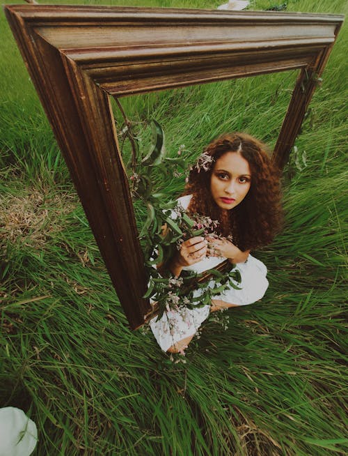 Woman in a White Dress Near a Wooden Frame on Green Grass