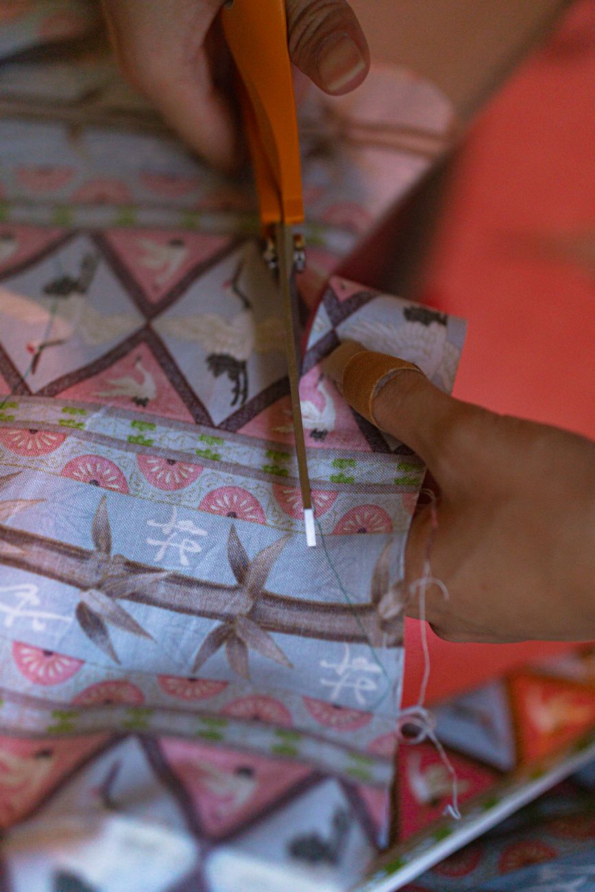 Hands cutting patterned fabric, the kind of labour that turns leftover cloth into a fresh proposition