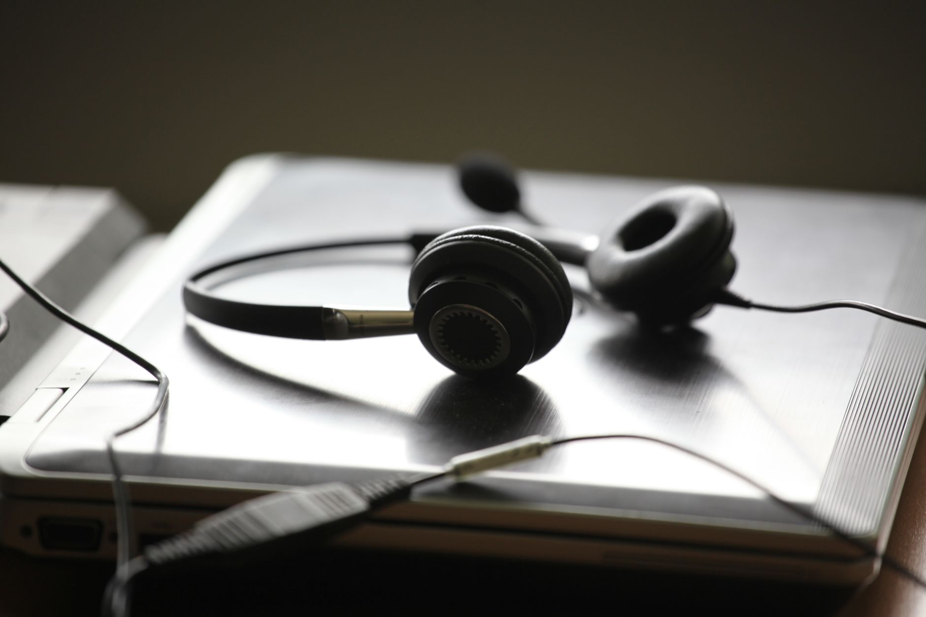 Black headphones lying on a closed silver laptop, symbolizing remote work or digital communication.