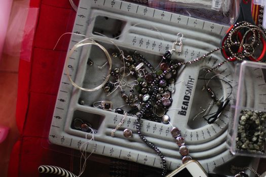 Capture of a jewelry-making workspace with beads, tools, and accessories laid out for crafting.