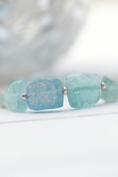 Close-up of aquamarine beads on white background in soft focus, highlighting elegance.