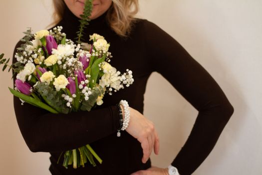 A Person in Black Long Sleeve Shirt with a Bouquet of Flowers Tucked on Arm