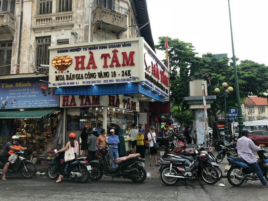 A lively street corner in Ho Chi Minh City with motorbikes and pedestrians, showcasing urban life.