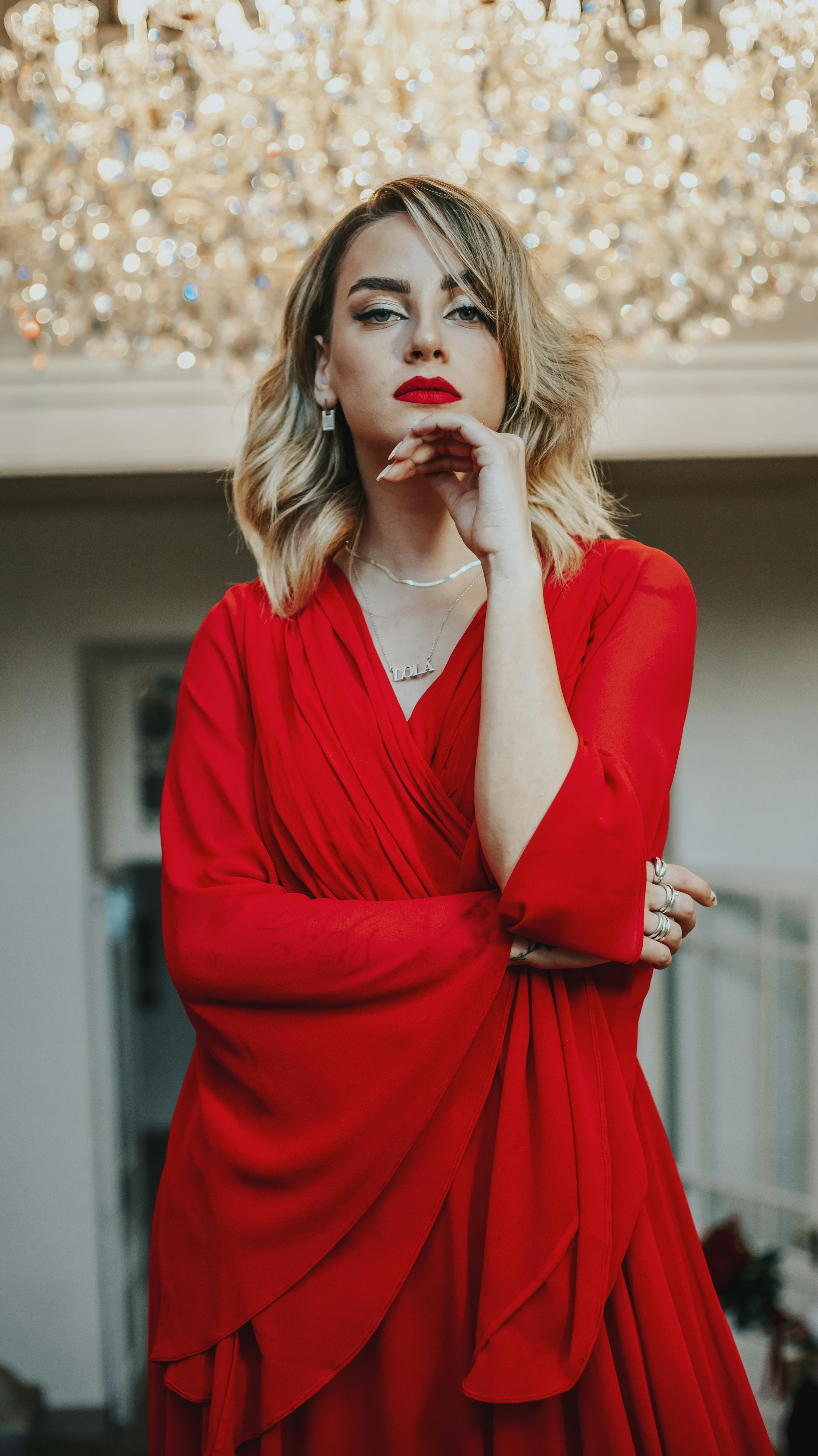 woman in red dress standing under a giant chandelier