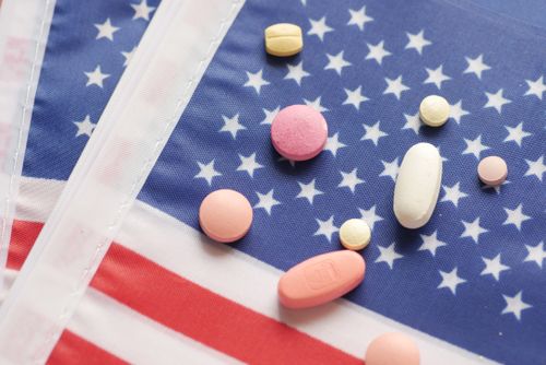 Free Various pills scattered over a printed American flag symbolizing healthcare. Stock Photo
