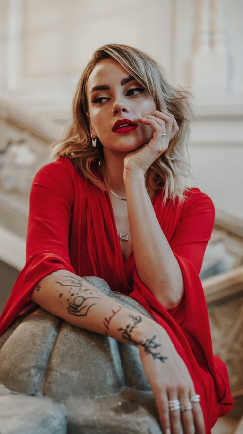 Free Sophisticated portrait of a woman in red with tattoos and jewelry, exuding modern elegance. Stock Photo