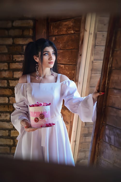 Woman in White Long Sleeve Dress Holding a Cake