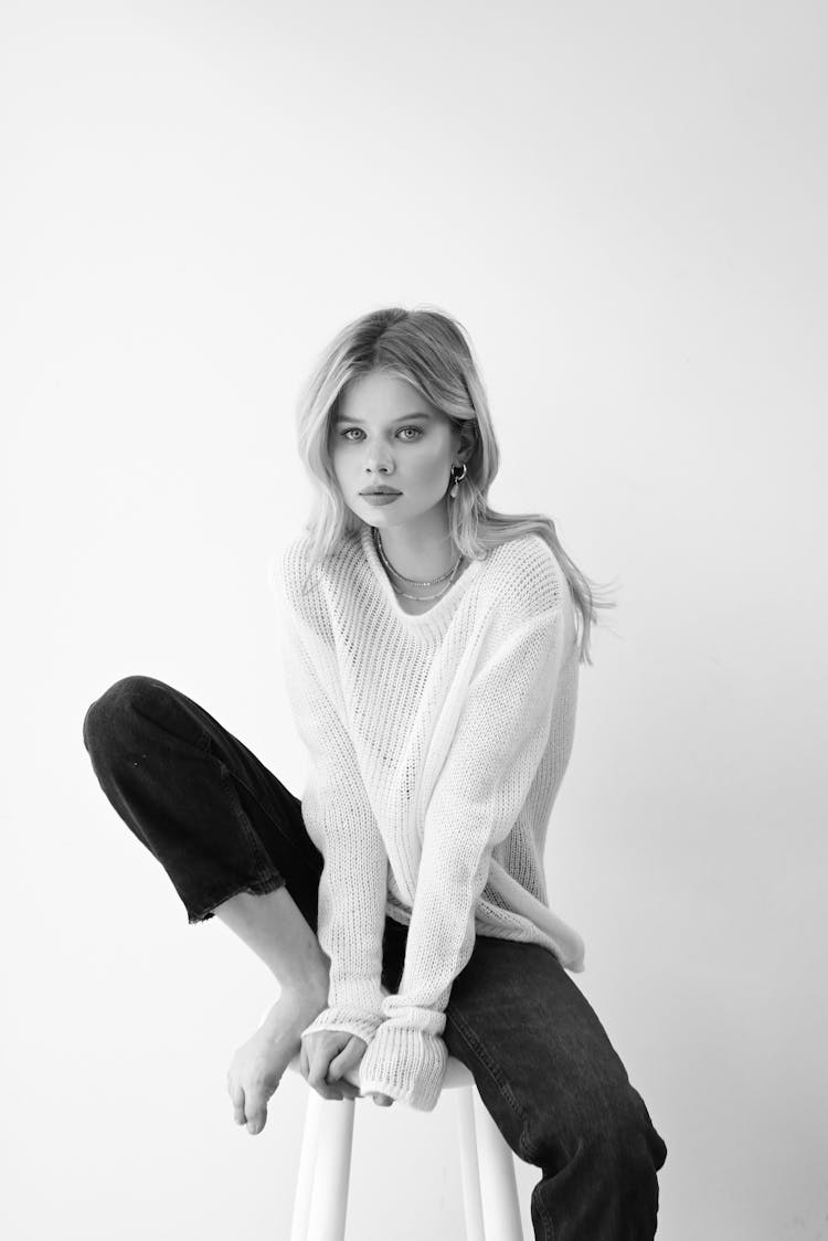 Black And White Photo Of A Young Woman Sitting On A Stool 