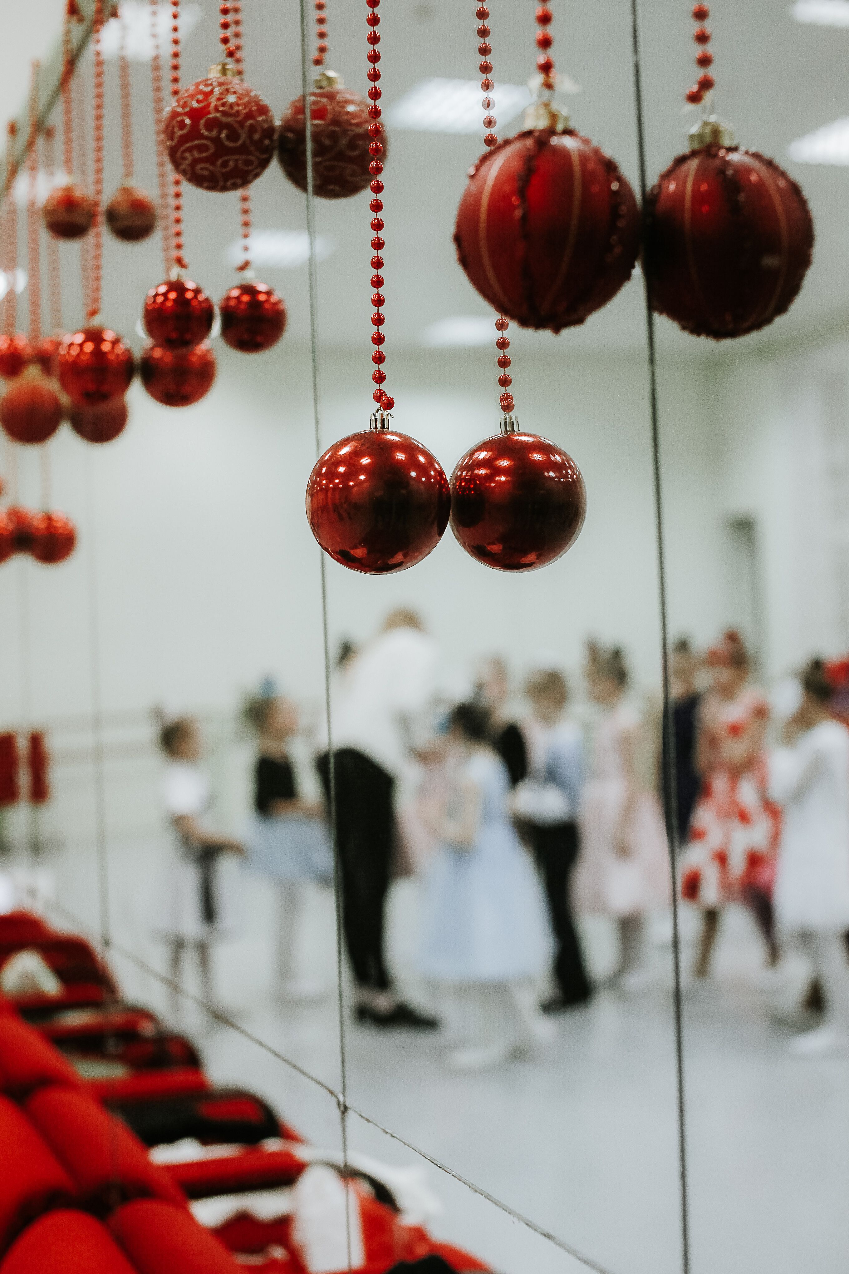 Close-up of red Christmas baubles with children dancing in the background