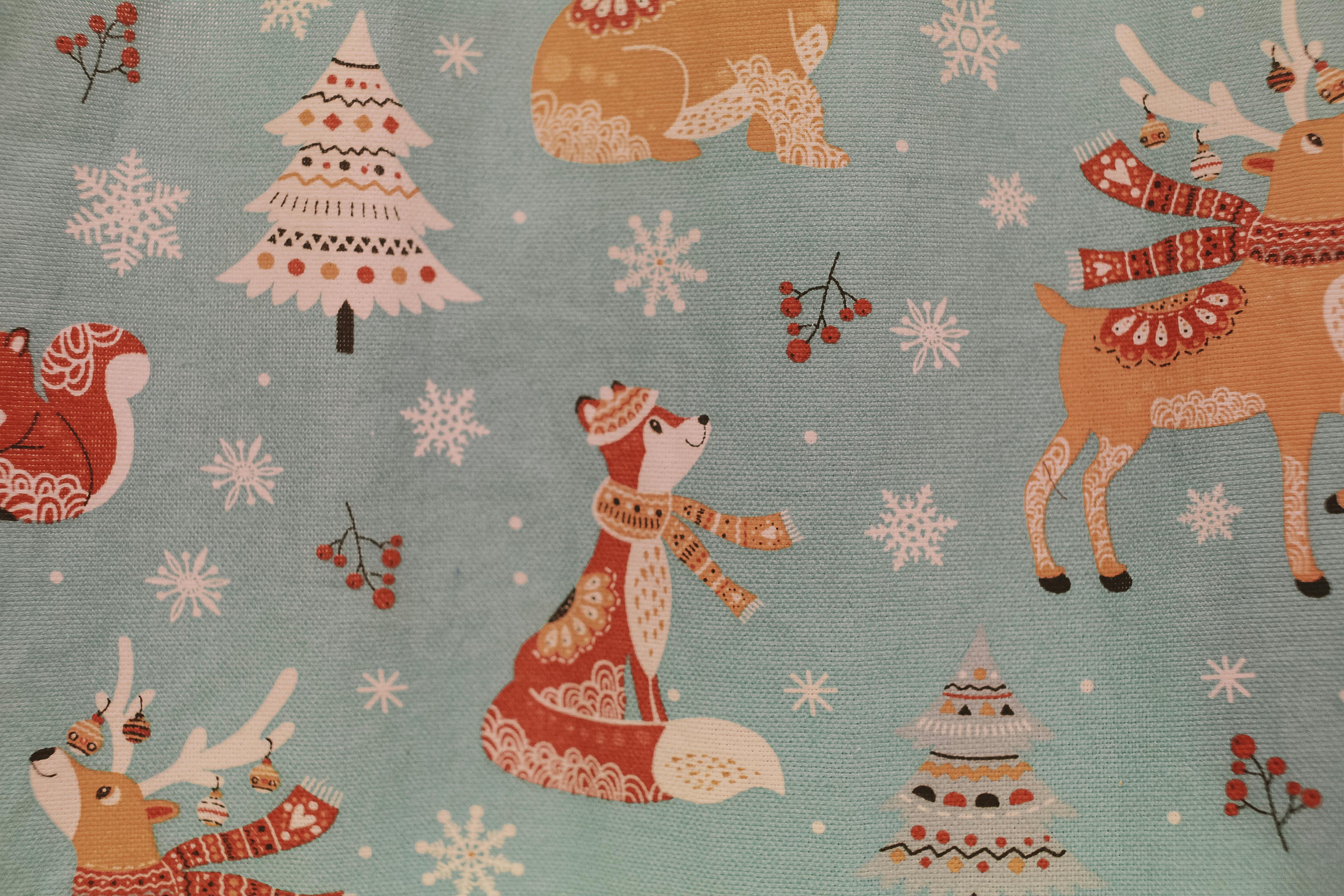Vibrant textile print with festive animals, snowflakes, and Christmas trees on a teal background.