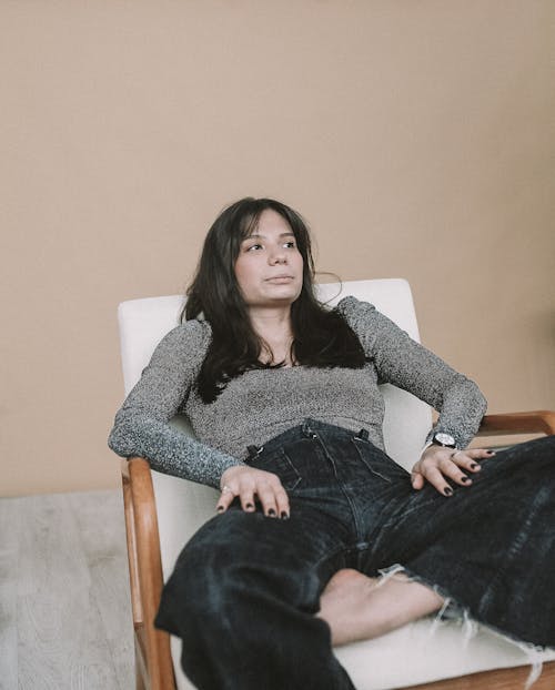 Free A Woman in Gray Long Sleeve Shirt Sitting on White Chair Stock Photo
