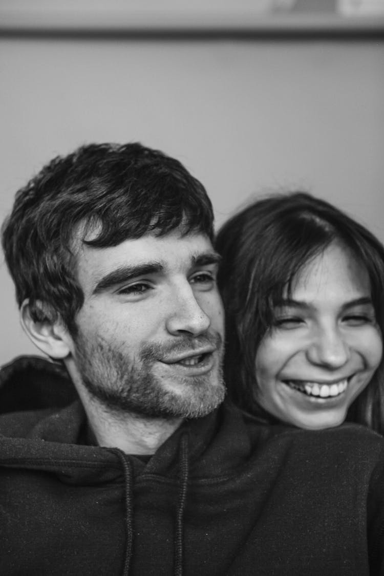 Young Woman Standing Behind Man And Resting Her Head On His Shoulder