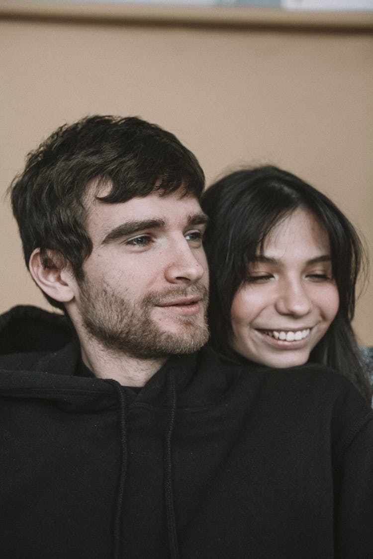 Woman With Long Black Hair Standing Behind Bearded Man And Smiling