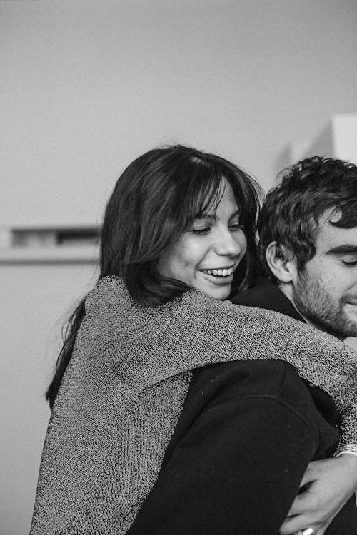 Grayscale Photo of a Woman Hugging a Man from Behind