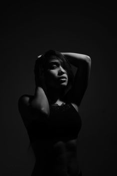A grayscale photo capturing the allure and mystery of a woman in a studio setting.