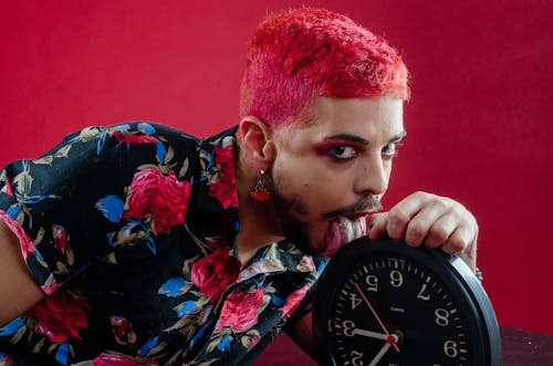 A Man with Dyed Hair Licking a Clock