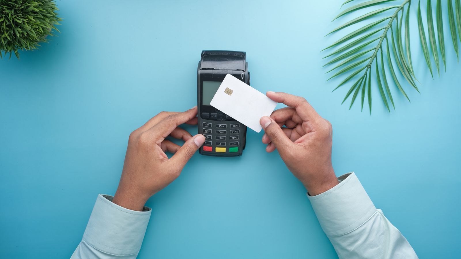 Hands using a contactless credit card on a payment terminal with a stylish minimal background.